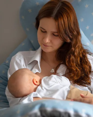 Front view of a mother holding her baby at home, showing love and care